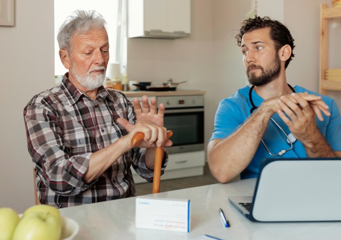 Kidan Medical provider talking with a senior patient at his kitchen table