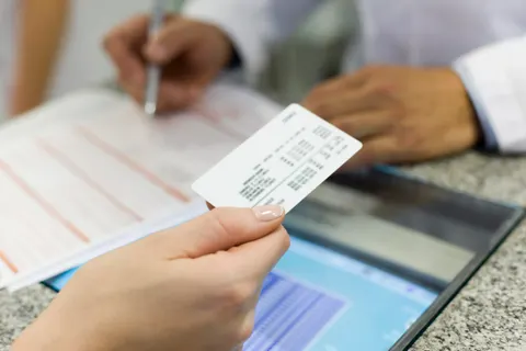 Patient handing over an insurance card to review coverage at Kidan Medical